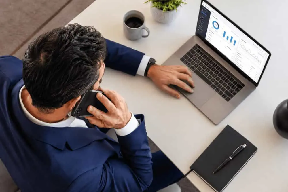 Professionnel au téléphone devant un tableau de bord sur ordinateur illustrant les étapes de la portabilité d'un numéro fixe professionnel.
